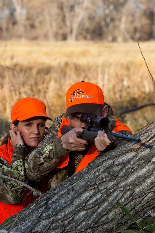 TC-Hunt-Women Big Game-D89992-00252.jpg :: Woman and man rifle hunting, river bottom, cottonwood trees, Max 1 camo, orange vest, hat, Elite Bushnell optics