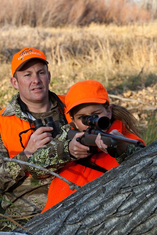 TC-Hunt-Women Big Game-D89992-00259.jpg :: Woman and man rifle hunting, river bottom, cottonwood trees, Max 1 camo, orange vest, hat, Elite Bushnell optics