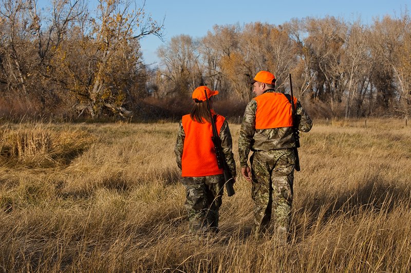 TC-Hunt-Women Big Game-D89992-00260.jpg :: Woman and man rifle hunting, river bottom, cottonwood trees, Max 1 camo, orange vest, hat, Elite Bushnell optics