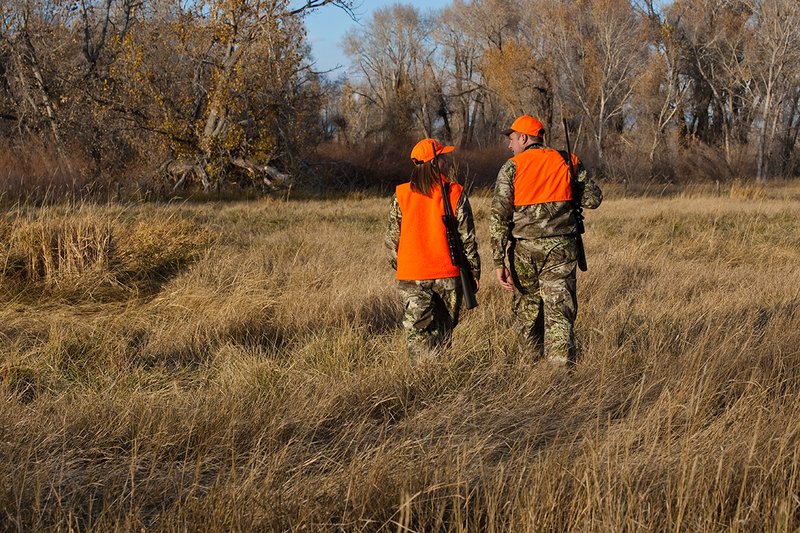 TC-Hunt-Women Big Game-D89992-00263.jpg :: Woman and man rifle hunting, river bottom, cottonwood trees, Max 1 camo, orange vest, hat, Elite Bushnell optics