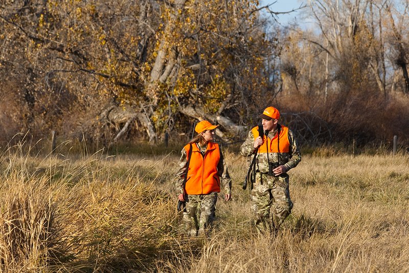 TC-Hunt-Women Big Game-D89992-00271.jpg :: Woman and man rifle hunting, river bottom, cottonwood trees, Max 1 camo, orange vest, hat, Elite Bushnell optics