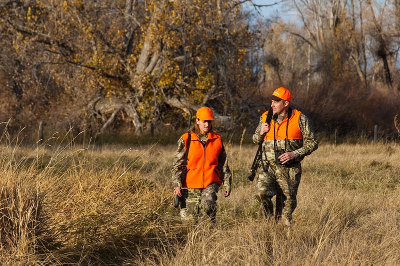 TC-Hunt-Women Big Game-D89992-00276.jpg :: Woman and man rifle hunting, river bottom, cottonwood trees, Max 1 camo, orange vest, hat, Elite Bushnell optics