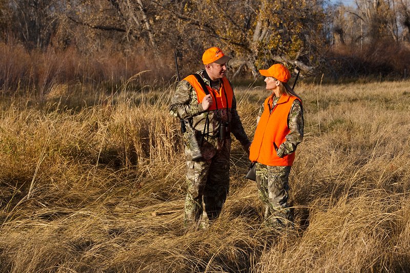 TC-Hunt-Women Big Game-D89992-00296.jpg :: Woman and man rifle hunting, river bottom, cottonwood trees, Max 1 camo, orange vest, hat, Elite Bushnell optics