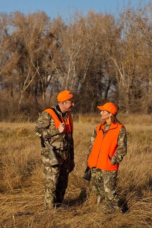 TC-Hunt-Women Big Game-D89992-00300.jpg :: Woman and man rifle hunting, river bottom, cottonwood trees, Max 1 camo, orange vest, hat, Elite Bushnell optics