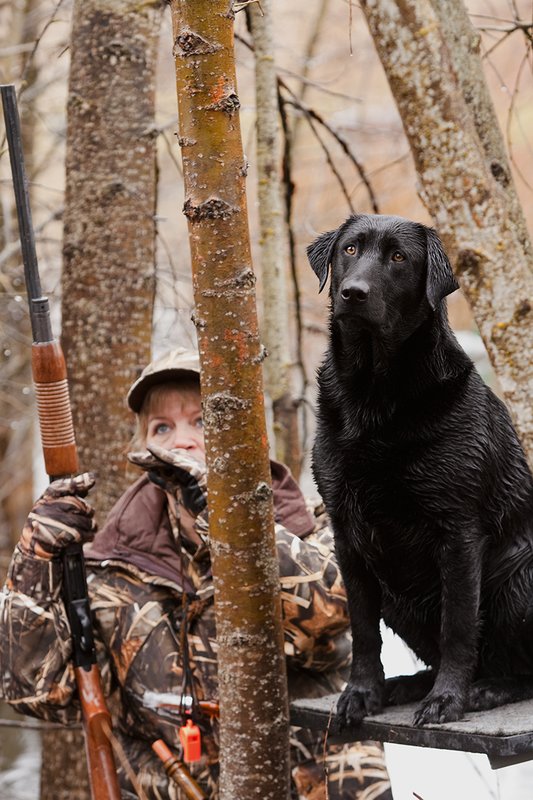 TC-Hunt-Women Waterfowl-D90081-00061.jpg :: Women Hunting Waterfowl in Flooded Timber, Advantage MaX-4HD Camo, Black Lab dog on platform