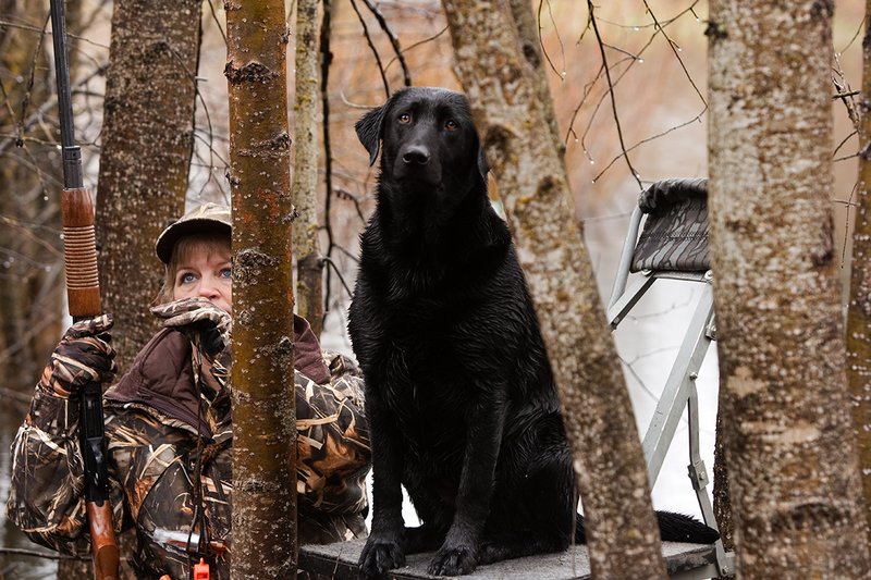 TC-Hunt-Women Waterfowl-D90081-00065.jpg :: Women Hunting Waterfowl in Flooded Timber, Advantage MaX-4HD Camo, Black Lab dog on platform