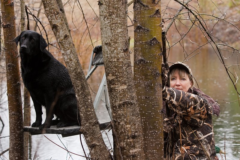 TC-Hunt-Women Waterfowl-D90081-00076.jpg :: Women Hunting Waterfowl in Flooded Timber, Advantage MaX-4HD Camo, Black Lab dog on platform