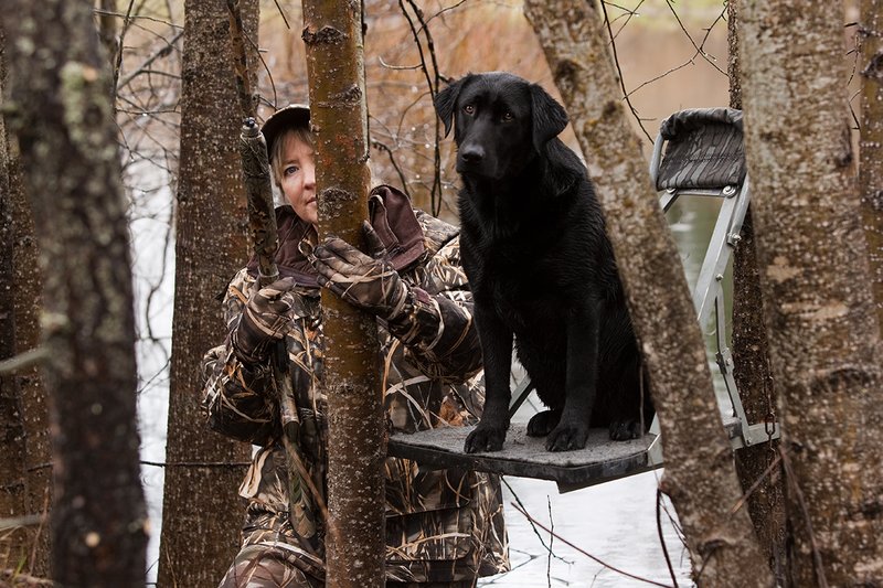 TC-Hunt-Women Waterfowl-D90081-00121.jpg :: Women Hunting Waterfowl in Flooded Timber, Advantage MaX-4HD Camo, Black Lab dog on platform