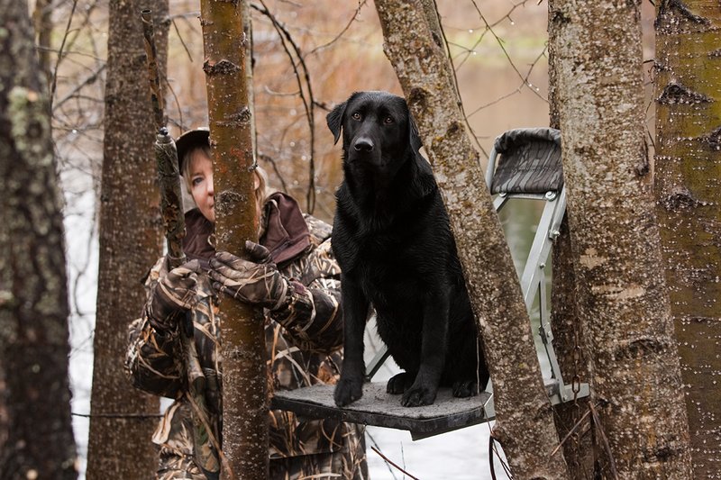 TC-Hunt-Women Waterfowl-D90081-00128.jpg :: Women Hunting Waterfowl in Flooded Timber, Advantage MaX-4HD Camo, Black Lab dog on platform