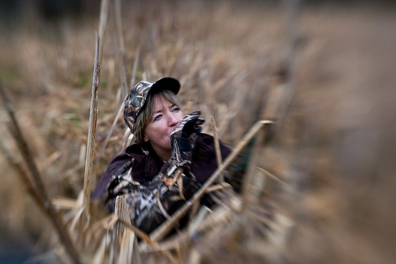 TC-Hunt-Women Waterfowl-D90081-00270.jpg :: Woman hunting waterfowl in cattails, wearing Advantage Max 4 camo, using call to lure birds in.
