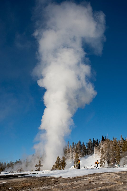 TC-Yellowstone winter-DYNP-W-00197.jpg :: Winter visitors to  Yellowstone National Park watch the Grand Geyser errupting in fridgid January air against a blue sky