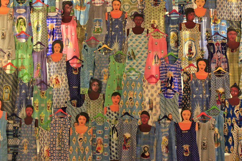 Installation Spoleto June 2013.jpg :: '' Ownership, identity and hybridization: Virginia Ryan's Shift/Rue de Commerce rotates around these concepts: reinterpreting, from a Western viewpoint, meanings and symbols that are intertwined in the colorful Pagne (wax printed cloths ) widely used in West Africa. Fundamentally ~but not exclusively ~ a woman's story, the cloths can be seen as actual 'semiotic mappings' in which ornamentation is but the most obvious of an iconographic meta~language presenting a world of dreams, hopes, ambition and power. It is not only a female story because the dresses (and elaborate head~dresses) made from the cloths empower the women with a regal beauty in their daily lives, but because it was women,such as the Togolese Nana Benz who created a veritable economic empire in the twentieth century by spreading the commerce in wax prints beyond national borders. To bring into the contemporary art world the history of these prints (which are not originally African, but rather Indonesian, where an ancient tradition of batik for sarongs and other clothing flourished) was the anglo~nigerian artist Yinka Shonibare MBE. With a touch of irony, Shonibare has interpreted this hybridization and in a sense, the disorientation occurring when considering that the material is marked by colonial histories in both a political and cultural sense. Colonial powers : Holland first,followed by Britain, had,by the middle of the 19th century,appropriated Indonesian techniques, used them to catalyze their textile industries before re~exporting to the markets of West Africa. These are the very cloths we, in the West, tend to think of as 'African'. Also in Shift/Rue Du Commerce we discover a strong connection with the story of the 'wax print',but rather than with an ironic gaze Virginia Ryan , born in Australia, intuitively attempts to create order from what may at first appear chaotic, by following the lure of primordial symbols also to be found in Aboriginal cultures. The work is conceived as a dialogue which plays on ambiguity, first and foremost linguistic.The word 'Shift' in English implies movement.But other meanings are also in use , such as the name for the classic dress designed by Coco Chanel in the 1920s, still a cult item. The second part of the title, Rue du Commerce has rather a precise geographic location whilst simultaneously referring back to meanings made more explicit in 'Shift'. Rue du Commerce is born,rather, from the very action of the artist walking with her ever~present camera , her vision already framing the photographic image.Walking along the shopping street of Rue du Commerce in the Plateau area of Abidjan,the artist began photographing the rows of Pagne visible in the boutique windows. 'Revisiting those photographs on the computer screen,where the very image is flattened , I perceived them as being divorced from the initial visual experience\