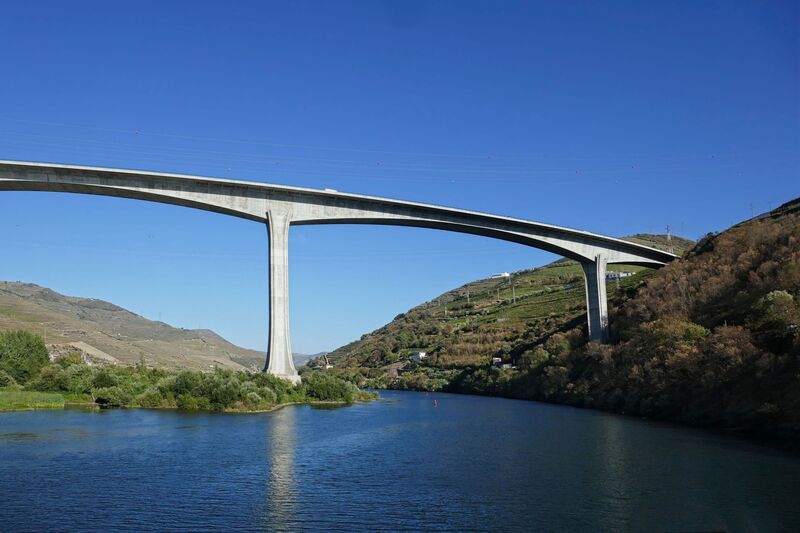 DC 22-0789-018.jpg :: Saga Douro River Cruise, Regua Lamego to Pinhao, River Douro: The Ponte Miguel Torga is a modern concrete viaduct carrying the A-24 highway across the Douro River near Peso da Régua, and is named after the renowned 20th-century Portuguese writer Miguel Torga. The 900-meter-long bridge features a continuous prestressed concrete box girder deck and a large 180-meter span over the river. Photo taken 30/08/2022.