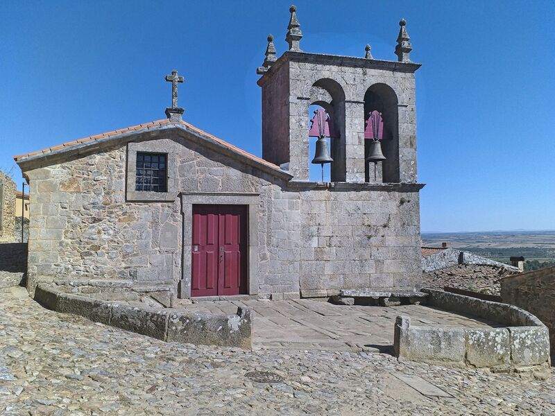 DC 22-0791-054.jpg :: Saga Douro River Cruise, Barca d'Alva, Castelo Rodrigo: The Mother Church is dedicated to Our Lady of Rocamador, and was founded in the thirteenth century by the Confraternity of the Friars of Our Lady of Rocamador, a congregation that was dedicated to assisting Compostela pilgrims. The Property maintains the primitive typology, it is an example of transition between Romanesque and Gothic, but it underwent later works, namely in the sixteenth and seventeenth centuries, which changed the structure of the temple. It has a composite plan, three naves, straight lintel porticoes and angular pediment. Inside we can admire a wooden coffered ceiling painted with hagiographic scenes, in the chancel eighteenth-century blue and white tiles and in the main altar Hispano-Arabic tiles. The Church was restored in the late 90s as part of the Historical Villages of Portugal Program. Photo taken 31/08/2022
