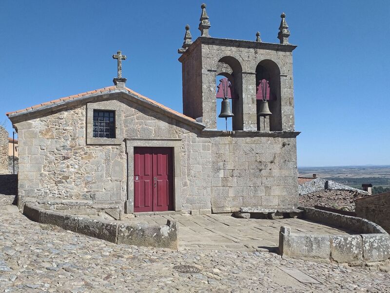 DC 22-0791-055.jpg :: Saga Douro River Cruise, Barca d'Alva, Castelo Rodrigo: The Mother Church is dedicated to Our Lady of Rocamador, and was founded in the thirteenth century by the Confraternity of the Friars of Our Lady of Rocamador, a congregation that was dedicated to assisting Compostela pilgrims. The Property maintains the primitive typology, it is an example of transition between Romanesque and Gothic, but it underwent later works, namely in the sixteenth and seventeenth centuries, which changed the structure of the temple. It has a composite plan, three naves, straight lintel porticoes and angular pediment. Inside we can admire a wooden coffered ceiling painted with hagiographic scenes, in the chancel eighteenth-century blue and white tiles and in the main altar Hispano-Arabic tiles. The Church was restored in the late 90s as part of the Historical Villages of Portugal Program. Photo taken 31/08/2022