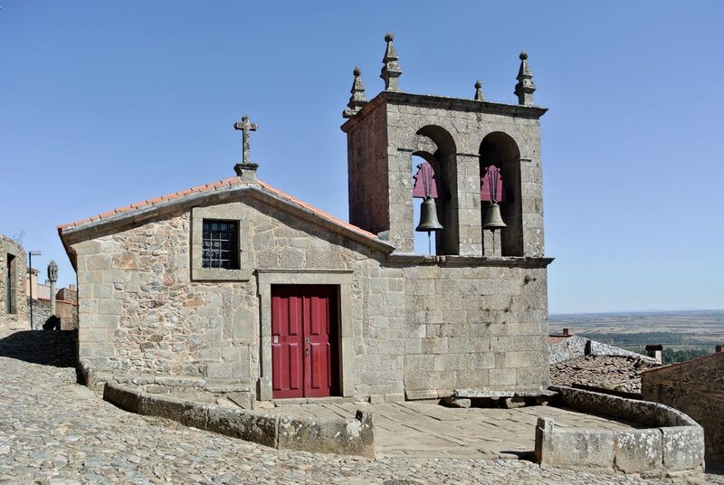DC 22-0791-057.jpg :: Saga Douro River Cruise, Barca d'Alva, Castelo Rodrigo: The Mother Church is dedicated to Our Lady of Rocamador, and was founded in the thirteenth century by the Confraternity of the Friars of Our Lady of Rocamador, a congregation that was dedicated to assisting Compostela pilgrims. The Property maintains the primitive typology, it is an example of transition between Romanesque and Gothic, but it underwent later works, namely in the sixteenth and seventeenth centuries, which changed the structure of the temple. It has a composite plan, three naves, straight lintel porticoes and angular pediment. Inside we can admire a wooden coffered ceiling painted with hagiographic scenes, in the chancel eighteenth-century blue and white tiles and in the main altar Hispano-Arabic tiles. The Church was restored in the late 90s as part of the Historical Villages of Portugal Program. Photo taken 31/08/2022