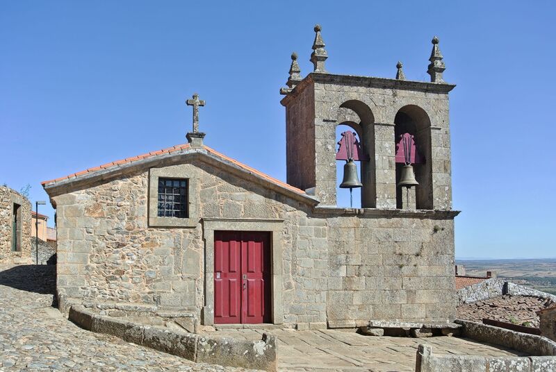 DC 22-0791-058.jpg :: Saga Douro River Cruise, Barca d'Alva, Castelo Rodrigo: The Mother Church is dedicated to Our Lady of Rocamador, and was founded in the thirteenth century by the Confraternity of the Friars of Our Lady of Rocamador, a congregation that was dedicated to assisting Compostela pilgrims. The Property maintains the primitive typology, it is an example of transition between Romanesque and Gothic, but it underwent later works, namely in the sixteenth and seventeenth centuries, which changed the structure of the temple. It has a composite plan, three naves, straight lintel porticoes and angular pediment. Inside we can admire a wooden coffered ceiling painted with hagiographic scenes, in the chancel eighteenth-century blue and white tiles and in the main altar Hispano-Arabic tiles. The Church was restored in the late 90s as part of the Historical Villages of Portugal Program. Photo taken 31/08/2022