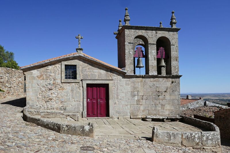 DC 22-0791-059.jpg :: Saga Douro River Cruise, Barca d'Alva, Castelo Rodrigo: The Mother Church is dedicated to Our Lady of Rocamador, and was founded in the thirteenth century by the Confraternity of the Friars of Our Lady of Rocamador, a congregation that was dedicated to assisting Compostela pilgrims. The Property maintains the primitive typology, it is an example of transition between Romanesque and Gothic, but it underwent later works, namely in the sixteenth and seventeenth centuries, which changed the structure of the temple. It has a composite plan, three naves, straight lintel porticoes and angular pediment. Inside we can admire a wooden coffered ceiling painted with hagiographic scenes, in the chancel eighteenth-century blue and white tiles and in the main altar Hispano-Arabic tiles. The Church was restored in the late 90s as part of the Historical Villages of Portugal Program. Photo taken 31/08/2022