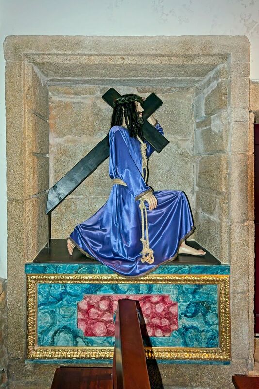 DC 22-0791-064.jpg :: Saga Douro River Cruise, Barca d'Alva, Castelo Rodrigo: The Mother Church is dedicated to Our Lady of Rocamador, and was founded in the thirteenth century by the Confraternity of the Friars of Our Lady of Rocamador, a congregation that was dedicated to assisting Compostela pilgrims. The Property maintains the primitive typology, it is an example of transition between Romanesque and Gothic, but it underwent later works, namely in the sixteenth and seventeenth centuries, which changed the structure of the temple. It has a composite plan, three naves, straight lintel porticoes and angular pediment. Inside we can admire a wooden coffered ceiling painted with hagiographic scenes, in the chancel eighteenth-century blue and white tiles and in the main altar Hispano-Arabic tiles. The Church was restored in the late 90s as part of the Historical Villages of Portugal Program. P.s. Christ carrying the cross. Photo taken 31/08/2022