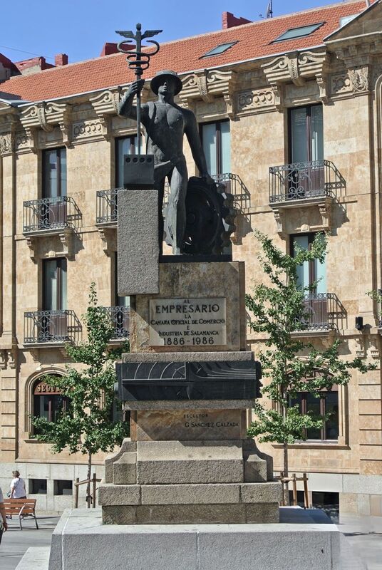 DC 22-0794-026.jpg :: Saga Douro River Cruise, Salamanca. Spain: This is the Monumento al Empresario (Monument to the Businessman) in Salamanca. The monument is located on the Gran Vía in Salamanca. It was created by the sculptor Gabriel Sánchez Calzada. The text on the pedestal refers to the Salamanca Official Chamber of Commerce (Cámara Oficial de Comercio) and the years 1886-1986. The figure holds a caduceus, a symbol often associated with commerce and negotiation. The bronze sculpture depicts the Roman god Mercury (Hermes in Greek mythology), who is considered the god of commerce, among other things. He is shown holding a caduceus, his traditional symbol, and wearing a hat. Photo taken 01/09/2022