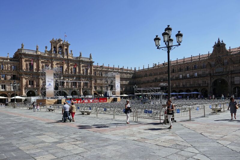 DC 22-0794-028.jpg :: Saga Douro River Cruise, Salamanca. Spain: The famous Plaza Mayor in Salamanca. Widely considered one of the most beautiful squares in the country, it is a significant example of Spanish Baroque architecture built in the 18th century. The Plaza Mayor is in the heart of Salamanca, a pedestrianized area that serves as the city's main social hub. It was primarily designed by architect Alberto Churriguera and completed in 1755. The buildings feature a uniform design of three stories, with arcades lining the perimeter and medallions depicting historic figures above the arches. Historically used for markets, bullfights, and public ceremonies, today the square is lined with numerous shops, restaurants, and cafes. It frequently hosts local events, concerts, and festivals, which explains the stage and seating setup. Photo taken 01/09/2022