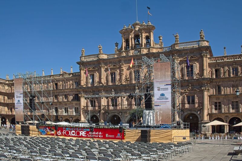 DC 22-0794-029.jpg :: Saga Douro River Cruise, Salamanca. Spain: The famous Plaza Mayor in Salamanca. Widely considered one of the most beautiful squares in the country, it is a significant example of Spanish Baroque architecture built in the 18th century. The Plaza Mayor is in the heart of Salamanca, a pedestrianized area that serves as the city's main social hub. It was primarily designed by architect Alberto Churriguera and completed in 1755. The buildings feature a uniform design of three stories, with arcades lining the perimeter and medallions depicting historic figures above the arches. Historically used for markets, bullfights, and public ceremonies, today the square is lined with numerous shops, restaurants, and cafes. It frequently hosts local events, concerts, and festivals, which explains the stage and seating setup. Photo taken 01/09/2022