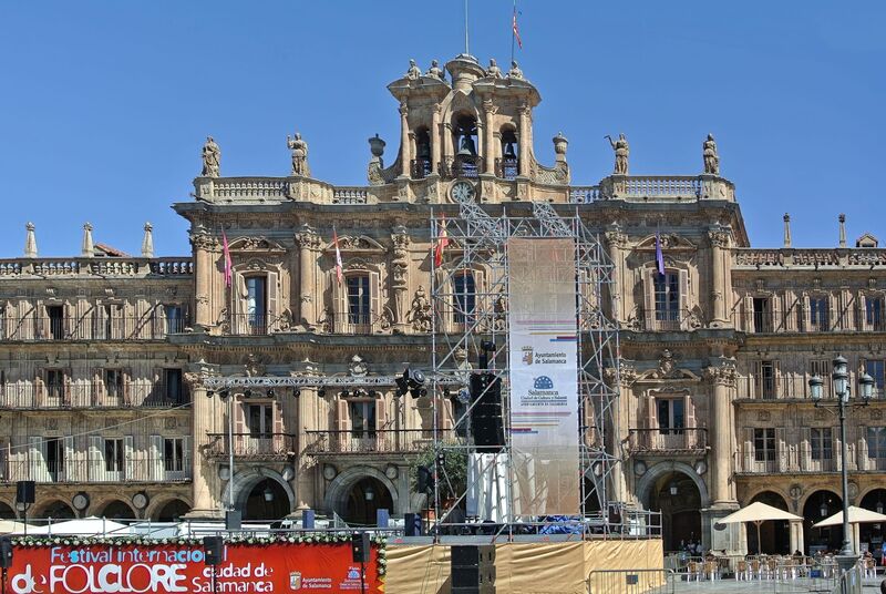 DC 22-0794-031.jpg :: Saga Douro River Cruise, Salamanca. Spain: The famous Plaza Mayor in Salamanca. Widely considered one of the most beautiful squares in the country, it is a significant example of Spanish Baroque architecture built in the 18th century. The Plaza Mayor is in the heart of Salamanca, a pedestrianized area that serves as the city's main social hub. It was primarily designed by architect Alberto Churriguera and completed in 1755. The buildings feature a uniform design of three stories, with arcades lining the perimeter and medallions depicting historic figures above the arches. Historically used for markets, bullfights, and public ceremonies, today the square is lined with numerous shops, restaurants, and cafes. It frequently hosts local events, concerts, and festivals, which explains the stage and seating setup. Photo taken 01/09/2022