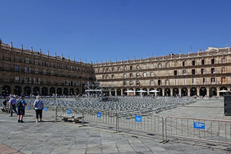 DC 22-0794-032.jpg :: Saga Douro River Cruise, Salamanca. Spain: The famous Plaza Mayor in Salamanca. Widely considered one of the most beautiful squares in the country, it is a significant example of Spanish Baroque architecture built in the 18th century. The Plaza Mayor is in the heart of Salamanca, a pedestrianized area that serves as the city's main social hub. It was primarily designed by architect Alberto Churriguera and completed in 1755. The buildings feature a uniform design of three stories, with arcades lining the perimeter and medallions depicting historic figures above the arches. Historically used for markets, bullfights, and public ceremonies, today the square is lined with numerous shops, restaurants, and cafes. It frequently hosts local events, concerts, and festivals, which explains the stage and seating setup. Photo taken 01/09/2022