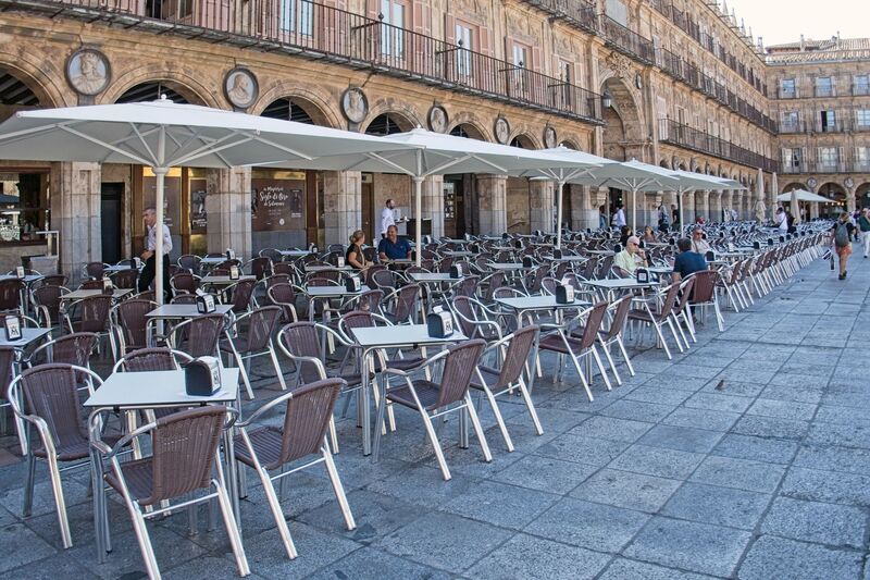DC 22-0794-035.jpg :: Saga Douro River Cruise, Salamanca. Spain: The famous Plaza Mayor in Salamanca. Widely considered one of the most beautiful squares in the country, it is a significant example of Spanish Baroque architecture built in the 18th century. The Plaza Mayor is in the heart of Salamanca, a pedestrianized area that serves as the city's main social hub. It was primarily designed by architect Alberto Churriguera and completed in 1755. The buildings feature a uniform design of three stories, with arcades lining the perimeter and medallions depicting historic figures above the arches. Historically used for markets, bullfights, and public ceremonies, today the square is lined with numerous shops, restaurants, and cafes. It frequently hosts local events, concerts, and festivals, which explains the stage and seating setup. Photo taken 01/09/2022