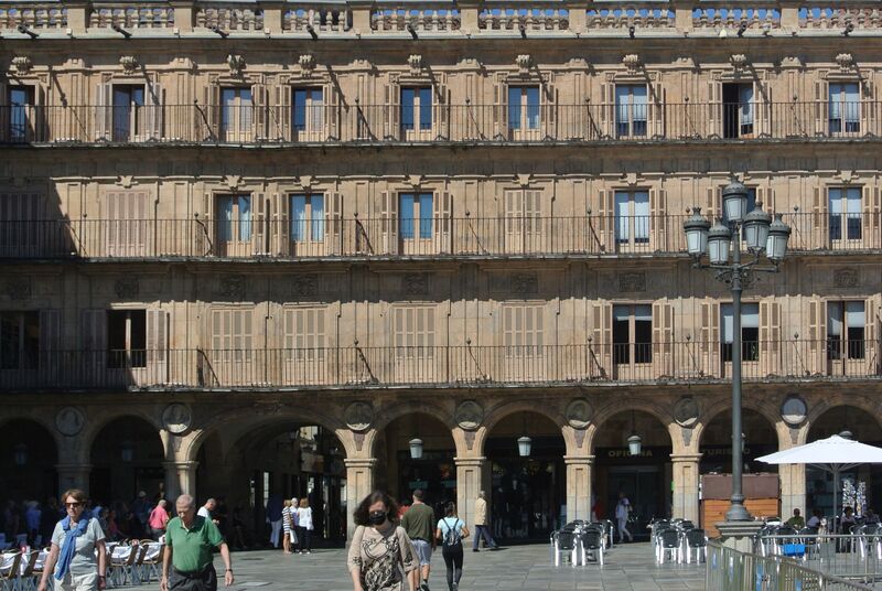 DC 22-0794-039.jpg :: Saga Douro River Cruise, Salamanca. Spain: The famous Plaza Mayor in Salamanca. Widely considered one of the most beautiful squares in the country, it is a significant example of Spanish Baroque architecture built in the 18th century. The Plaza Mayor is in the heart of Salamanca, a pedestrianized area that serves as the city's main social hub. It was primarily designed by architect Alberto Churriguera and completed in 1755. The buildings feature a uniform design of three stories, with arcades lining the perimeter and medallions depicting historic figures above the arches. Historically used for markets, bullfights, and public ceremonies, today the square is lined with numerous shops, restaurants, and cafes. It frequently hosts local events, concerts, and festivals, which explains the stage and seating setup. Photo taken 01/09/2022