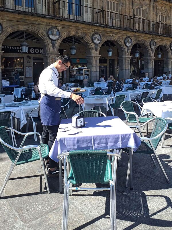 DC 22-0794-046.jpg :: Saga Douro River Cruise, Salamanca. Spain: The famous Plaza Mayor in Salamanca. Widely considered one of the most beautiful squares in the country, it is a significant example of Spanish Baroque architecture built in the 18th century. The Plaza Mayor is in the heart of Salamanca, a pedestrianized area that serves as the city's main social hub. It was primarily designed by architect Alberto Churriguera and completed in 1755. The buildings feature a uniform design of three stories, with arcades lining the perimeter and medallions depicting historic figures above the arches. Historically used for markets, bullfights, and public ceremonies, today the square is lined with numerous shops, restaurants, and cafes. It frequently hosts local events, concerts, and festivals, which explains the stage and seating setup. Photo taken 01/09/2022