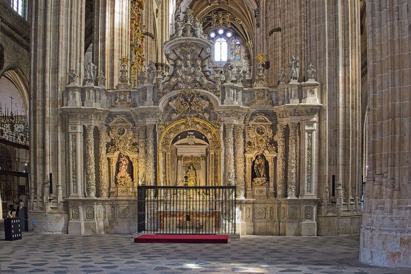 DC 22-0794-085.jpg :: Saga Douro River Cruise, Salamanca. Spain: The ornate interior of the New Cathedral of Salamanca (Catedral Nueva de Salamanca). The cathedral was constructed between the 16th and 18th centuries, resulting in a blend of late Gothic, Renaissance, and Baroque architectural styles. The interior is known for its immense height, with soaring Gothic ribbed vaults that draw the eye heavenward. The image focuses on a highly decorated structure, which is part of the Baroque-style choir or retrochoir, designed by artists including Alberto de Churriguera in the early 18th century. The nave is lined with various side chapels, each with its own unique artistic and architectural details, featuring richly decorated altarpieces and tombs. Medieval and Renaissance stained-glass windows flood the interior with coloured light. Photo taken 01/09/2022