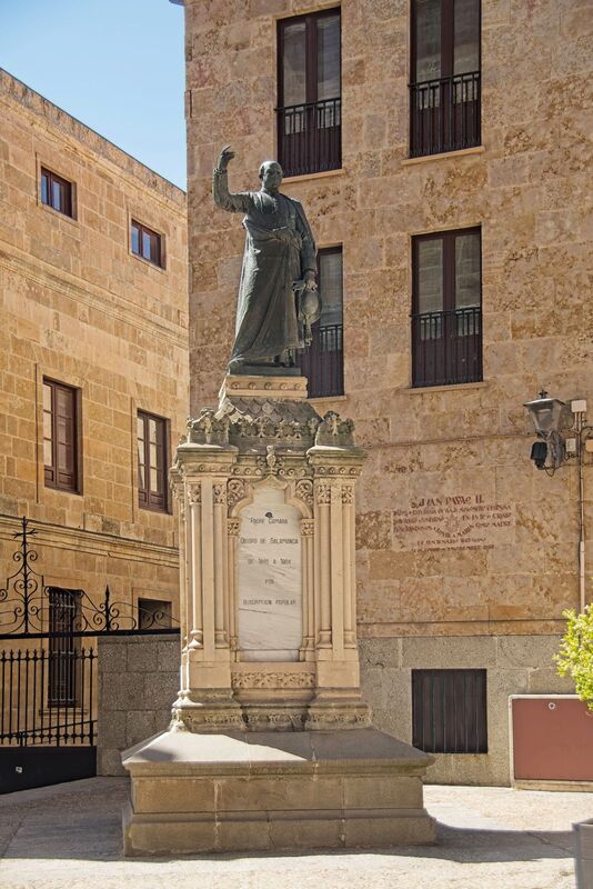 DC 22-0794-091.jpg :: Saga Douro River Cruise, Salamanca. Spain: The statue in the image is the Monumento al Padre Cámara (Monument to Father Cámara), dedicated to Tomás Jenaro de Cámara y Castro, the Bishop of Salamanca from 1885 until his death in 1904. The monument is situated in the historic city centre of Salamanca, Spain, in Plaza Juan XXIII, near the Episcopal Palace and in front of the cathedral doors. It is the work of Spanish sculptor Aniceto Marinas García. The bronze statue was originally erected in 1910 through public subscription in front of the Anaya Palace and later moved to its current location in 1974. The statue depicts Padre Cámara in his robes, with his right hand raised as if giving a blessing or sermon, holding gloves and a hat in his left hand. Tomás Cámara y Castro (1847-1904) was a prominent figure in the Spanish 19th century, known for his diverse activities Photo taken 01/09/2022
