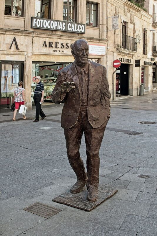 DC 22-0794-109.jpg :: Saga Douro River Cruise, Salamanca. Spain: The statue in the image is of Vicente del Bosque, the former coach of the Spanish national football team. The bronze statue is located in the Plaza del Liceo, in Salamanca, which is del Bosque's hometown. It was created by the local artist and sculptor Fernando Mayoral. The sculpture was unveiled on September 27, 2018, in a ceremony attended by del Bosque himself. The statue was erected to honour del Bosque's successful career, which included winning the World Cup in 2010 and the European Championship in 2012 as the national team manager. A plaque next to the statue lists these achievements. Photo taken 01/09/2022