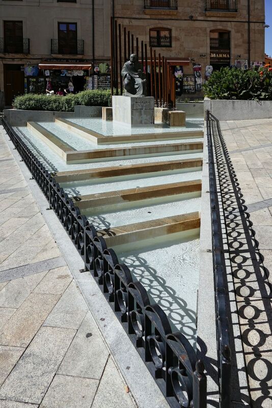 DC 22-0794-166.jpg :: Saga Douro River Cruise, Salamanca. Spain: The Monumento al Maestro Salinas (Monument to Maestro Salinas). The bronze sculpture, created by Hipólito Pérez Calvo and inaugurated in 1993, honours the life and work of Francisco de Salinas, a renowned 16th-century Spanish music theorist and organist. The statue depicts Francisco de Salinas, who became blind at age eleven but went on to become a famous musician and a professor of music at the University of Salamanca for over 20 years. The monument is situated in a triangular square at the intersection of Rúa Antigua, Rúa Mayor, and Calle Compañía. It is next to other significant landmarks, including the historic Casa de las Conchas and the Clerecía church (Pontifical University building). Photo taken 01/09/2022