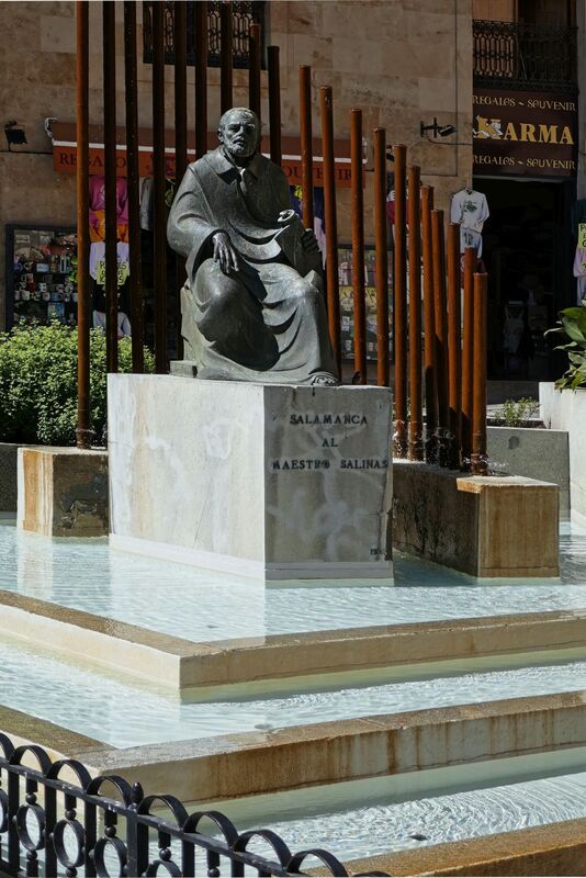 DC 22-0794-167.jpg :: Saga Douro River Cruise, Salamanca. Spain: The Monumento al Maestro Salinas (Monument to Maestro Salinas). The bronze sculpture, created by Hipólito Pérez Calvo and inaugurated in 1993, honours the life and work of Francisco de Salinas, a renowned 16th-century Spanish music theorist and organist. The statue depicts Francisco de Salinas, who became blind at age eleven but went on to become a famous musician and a professor of music at the University of Salamanca for over 20 years. The monument is situated in a triangular square at the intersection of Rúa Antigua, Rúa Mayor, and Calle Compañía. It is next to other significant landmarks, including the historic Casa de las Conchas and the Clerecía church (Pontifical University building). Photo taken 01/09/2022