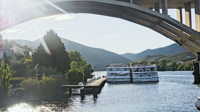 DC 22-0796-002.jpg :: Saga Douro River Cruise, Barca d'Alva, Portugal: Almirante Sarmento Rodrigues Bridge, also known locally as the Barca d'Alva Bridge. It spans the Douro River near the village of Barca d'Alva in Portugal, close to the border with Spain. The bridge is situated in the upper Douro region, specifically near the small village of Barca d'Alva, within the municipality of Freixo de Espada à Cinta, Portugal. It is one of the crossings over the picturesque Douro River, known for its terraced vineyards that produce port wine. The structure is a notable example of modern civil engineering, featuring large, graceful concrete arches supported by substantial pillars emerging from the river. The area around the bridge is part of the Douro International Natural Park and is a popular destination for tourists, including those on Douro River cruises and hikers exploring the region. Photo taken 01/09/2022