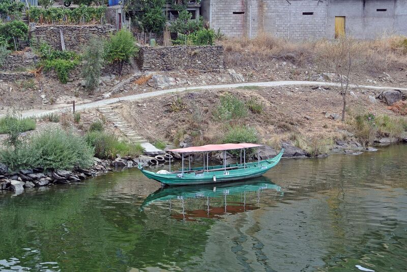 DC 22-0797-016.jpg :: Saga Douro River Cruise, Pocinho to Pinhao, River Douro The MS Douro Spirit sailing passing Foz do Tua in the Castanheiro Region, along the Douro River, onward to Pinhao. A rabelo boat, a traditional Portuguese wooden vessel unique to the Douro River region, which includes the area around Tua. Rabelo boats were historically used to transport barrels of port wine from the vineyards in the Alto Douro region downstream to the wine cellars in Vila Nova de Gaia, near Porto. They are flat-bottomed with a shallow draught, designed specifically to navigate the once-turbulent, shallow, and fast-flowing waters of the undammed Douro River. Photo taken 02/09/2022
