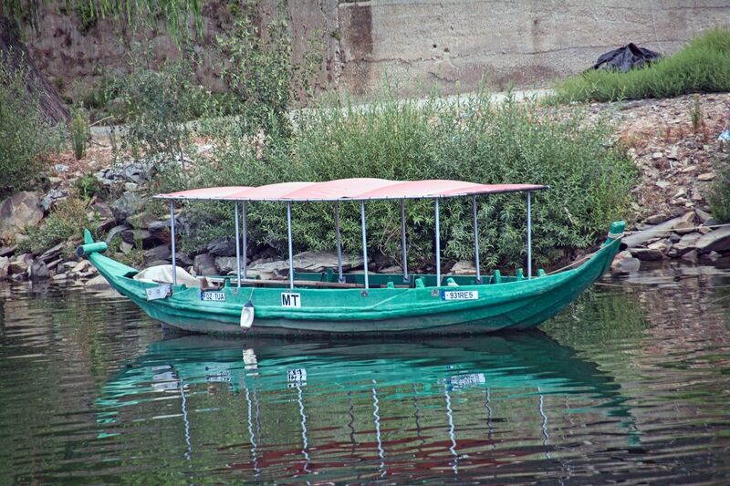 DC 22-0797-017.jpg :: Saga Douro River Cruise, Pocinho to Pinhao, River Douro The MS Douro Spirit sailing passing Foz do Tua in the Castanheiro Region, along the Douro River, onward to Pinhao. A rabelo boat, a traditional Portuguese wooden vessel unique to the Douro River region, which includes the area around Tua. Rabelo boats were historically used to transport barrels of port wine from the vineyards in the Alto Douro region downstream to the wine cellars in Vila Nova de Gaia, near Porto. They are flat-bottomed with a shallow draught, designed specifically to navigate the once-turbulent, shallow, and fast-flowing waters of the undammed Douro River. Photo taken 02/09/2022