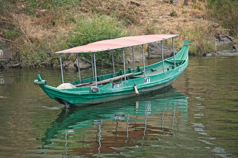 DC 22-0797-018.jpg :: Saga Douro River Cruise, Pocinho to Pinhao, River Douro The MS Douro Spirit sailing passing Foz do Tua in the Castanheiro Region, along the Douro River, onward to Pinhao. A rabelo boat, a traditional Portuguese wooden vessel unique to the Douro River region, which includes the area around Tua. Rabelo boats were historically used to transport barrels of port wine from the vineyards in the Alto Douro region downstream to the wine cellars in Vila Nova de Gaia, near Porto. They are flat-bottomed with a shallow draught, designed specifically to navigate the once-turbulent, shallow, and fast-flowing waters of the undammed Douro River. Photo taken 02/09/2022