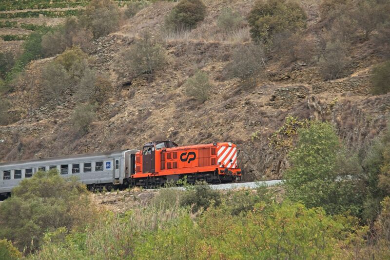 DC 22-0797-029.jpg :: Saga Douro River Cruise, Pocinho to Pinhao, River Douro: MS Douro Spirit passing the area of Castedo e Cotas on the River Douro. The locomotive in the image is a CP Class 1400, a series of diesel-electric locomotives built for the Portuguese Railways (CP). The train is operated by CP (Comboios de Portugal), the state-owned Portuguese railway company, as indicated by the logo on its side. The locomotives were designed by English Electric and built between 1967 and 1969. The first ten were built in England, while the rest were assembled in Portugal by Sorefame. The Class 1400 is mechanically based on the British Rail Class 20 locomotive but uses a more powerful engine and has its cab positioned away from the extreme end. These locomotives were originally ordered to replace the remaining steam locomotives in service. Many remain in service today, some with private operators. They are often seen on lines like the Douro Valley line. Photo taken 02/09/2022