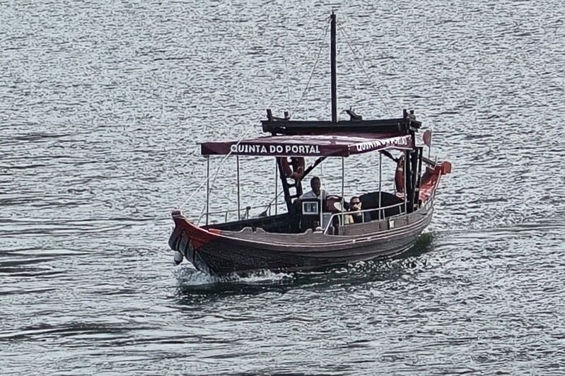 DC 22-0797-039.jpg :: Saga Douro River Cruise, Pocinho to Pinhao, River Douro: MS Douro Spirit passing the area of Praia de Douro on the River Douro. A traditional Portuguese rabelo boat on the Douro River, advertising the wine estate Quinta do Portal. Rabelo boats were historically used to transport barrels of Port wine from the vineyards in the Douro Valley to the aging cellars in Vila Nova de Gaia. Photo taken 02/09/2022