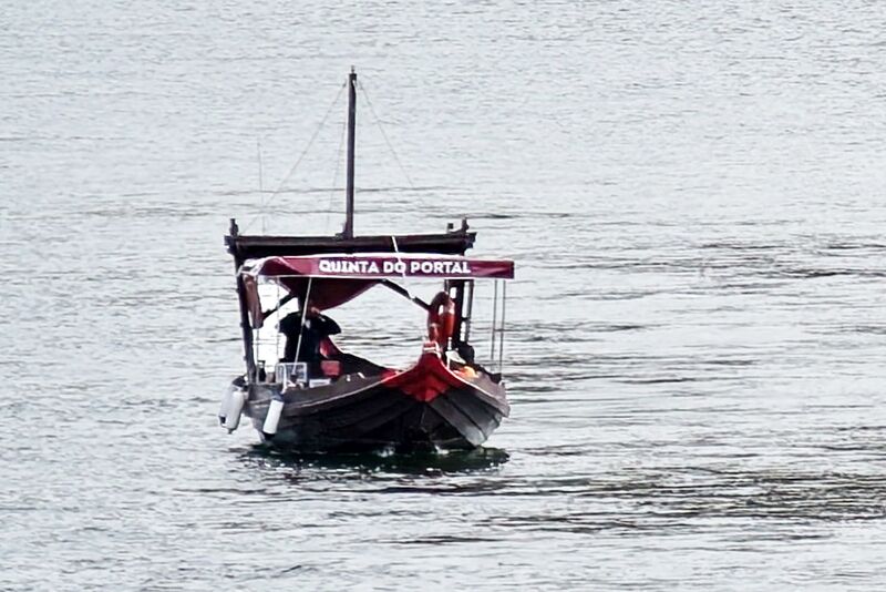 DC 22-0797-042.jpg :: Saga Douro River Cruise, Pocinho to Pinhao, River Douro: MS Douro Spirit passing the area of Praia de Douro on the River Douro. A traditional Portuguese rabelo boat on the Douro River, advertising the wine estate Quinta do Portal. Rabelo boats were historically used to transport barrels of Port wine from the vineyards in the Douro Valley to the aging cellars in Vila Nova de Gaia. Photo taken 02/09/2022