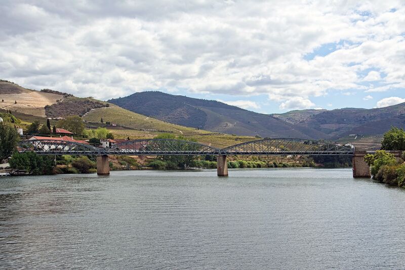 DC 22-0797-068.jpg :: Saga Douro River Cruise, Pocinho to Pinhao, River Douro: The Ponte do Pinhão, a steel road bridge crossing the Douro River in the village of Pinhão, Portugal. This bridge is often referred to as the Gustave Eiffel bridge as it was designed by the famous French engineer Gustave Eiffel and his firm. Spans the Douro River in Pinhão, Portugal, connecting both banks of the river in the heart of the Alto Douro Wine Region. Opened in 1903. It was designed in the late 19th century. It is a road bridge that carries traffic and has pedestrian walkways, serving as an essential link for local residents and a scenic spot for tourists. Photo taken 02/09/2022
