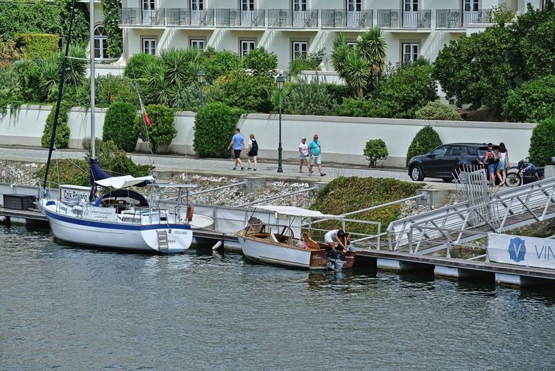 DC 22-0797-077.jpg :: Saga Douro River Cruise, Pocinho to Pinhao, River Douro: The village pictured in the image is Pinhão, a picturesque town nestled in the heart of Portugal's renowned Douro Valley wine region. The image shows the town from across the Douro River, featuring its distinctive iron bridge and the surrounding terraced hills covered in vineyards. Pinhão is located in the Norte Region of Portugal, within the Douro Valley, which is a UNESCO World Heritage site known for its stunning landscapes and port wine production. Photo taken 02/09/2022