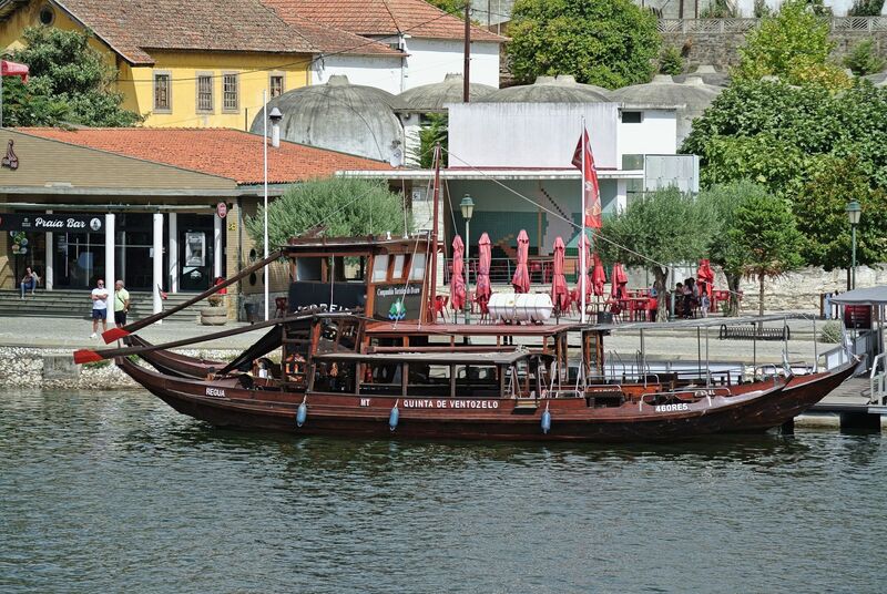 DC 22-0797-081.jpg :: Saga Douro River Cruise, Pocinho to Pinhao, River Douro: A traditional Portuguese rabelo boat docked in Pinhão, Portugal, likely used for tourist cruises on the Douro River. Rabelo boats traditionally transported barrels of Port wine from the Douro Valley vineyards to Vila Nova de Gaia. Modern versions, like the one pictured, are built for passengers and meet contemporary safety standards. These boats offer tours through the scenic, terraced vineyards of the UNESCO World Heritage region. Photo taken 02/09/2022