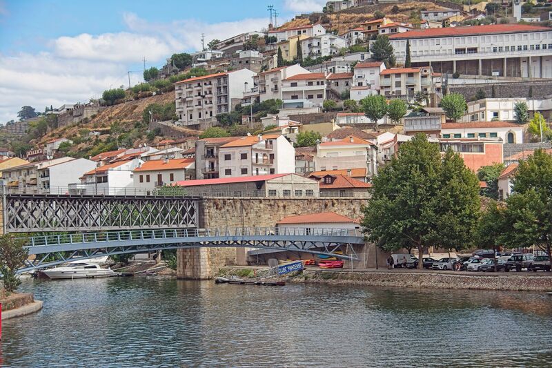 DC 22-0797-106.jpg :: Saga Douro River Cruise, Pocinho to Pinhao, River Douro: The Pinhão Railway Bridge, a prominent truss bridge that spans the Pinhão River at its confluence with the Douro River in Portugal. The structure is part of the historic Linha do Douro (Douro Line), which is renowned for its scenic views of the UNESCO-listed Douro Valley wine region. The bridge features a classic metal lattice truss design supported by robust stone masonry piers that extend into the water. It serves the Pinhão railway station, located nearby, which is famous for its traditional blue-and-white tile (azulejo) panels depicting the region's viticulture. Photo taken 02/09/2022
