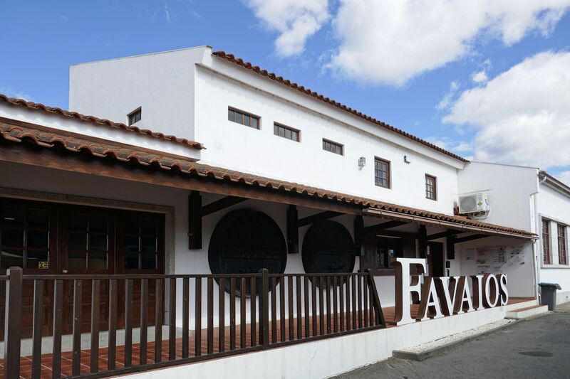 DC 22-0808-025.jpg :: Saga Douro River Cruise, Favaios:  The building in the image is the Adega Cooperativa de Favaios, a renowned winery located in the village of Favaios within the Douro wine region of Portugal. The winery is famous for producing one of Portugal's most iconic fortified wines, Moscatel de Favaios. The winery is nestled in the picturesque Alto Douro wine region of Portugal, a UNESCO World Heritage site. Founded in 1952, the cooperative was established by local producers to create their famous Moscatel wine. While most famous for its Moscatel, the winery also produces DOC Douro wines (white, red, and rosé), sparkling wines, and Port wine. Photo taken 02/09/2022