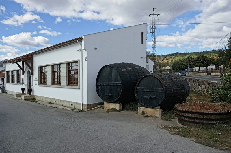 DC 22-0808-027.jpg :: Saga Douro River Cruise, Favaios:  The building in the image is the Adega Cooperativa de Favaios, a renowned winery located in the village of Favaios within the Douro wine region of Portugal. The winery is famous for producing one of Portugal's most iconic fortified wines, Moscatel de Favaios. The winery is nestled in the picturesque Alto Douro wine region of Portugal, a UNESCO World Heritage site. Founded in 1952, the cooperative was established by local producers to create their famous Moscatel wine. While most famous for its Moscatel, the winery also produces DOC Douro wines (white, red, and rosé), sparkling wines, and Port wine. Photo taken 02/09/2022