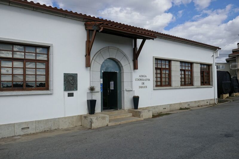 DC 22-0808-028.jpg :: Saga Douro River Cruise, Favaios:  The building in the image is the Adega Cooperativa de Favaios, a renowned winery located in the village of Favaios within the Douro wine region of Portugal. The winery is famous for producing one of Portugal's most iconic fortified wines, Moscatel de Favaios. The winery is nestled in the picturesque Alto Douro wine region of Portugal, a UNESCO World Heritage site. Founded in 1952, the cooperative was established by local producers to create their famous Moscatel wine. While most famous for its Moscatel, the winery also produces DOC Douro wines (white, red, and rosé), sparkling wines, and Port wine. Photo taken 02/09/2022